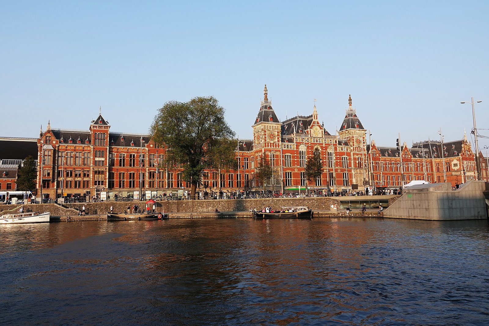 Station Amsterdam Centraal in de avondzon, gezien over het water