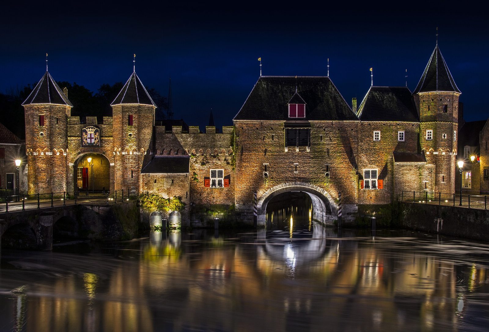 De Koppelpoort in Amersfoort, 's avonds verlicht en weerspiegeld in het water